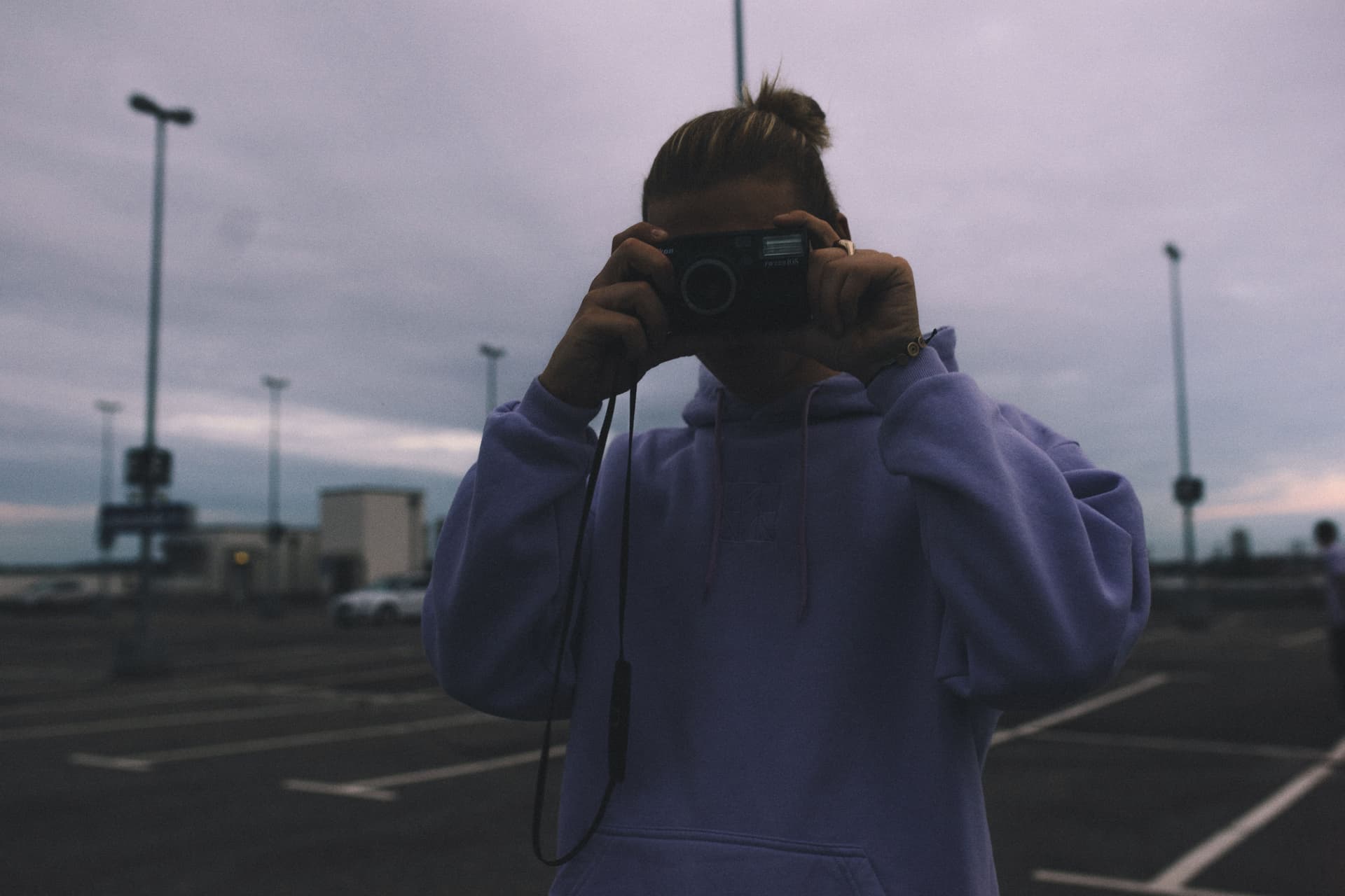 A male model pointing with an analoge camera at the camera